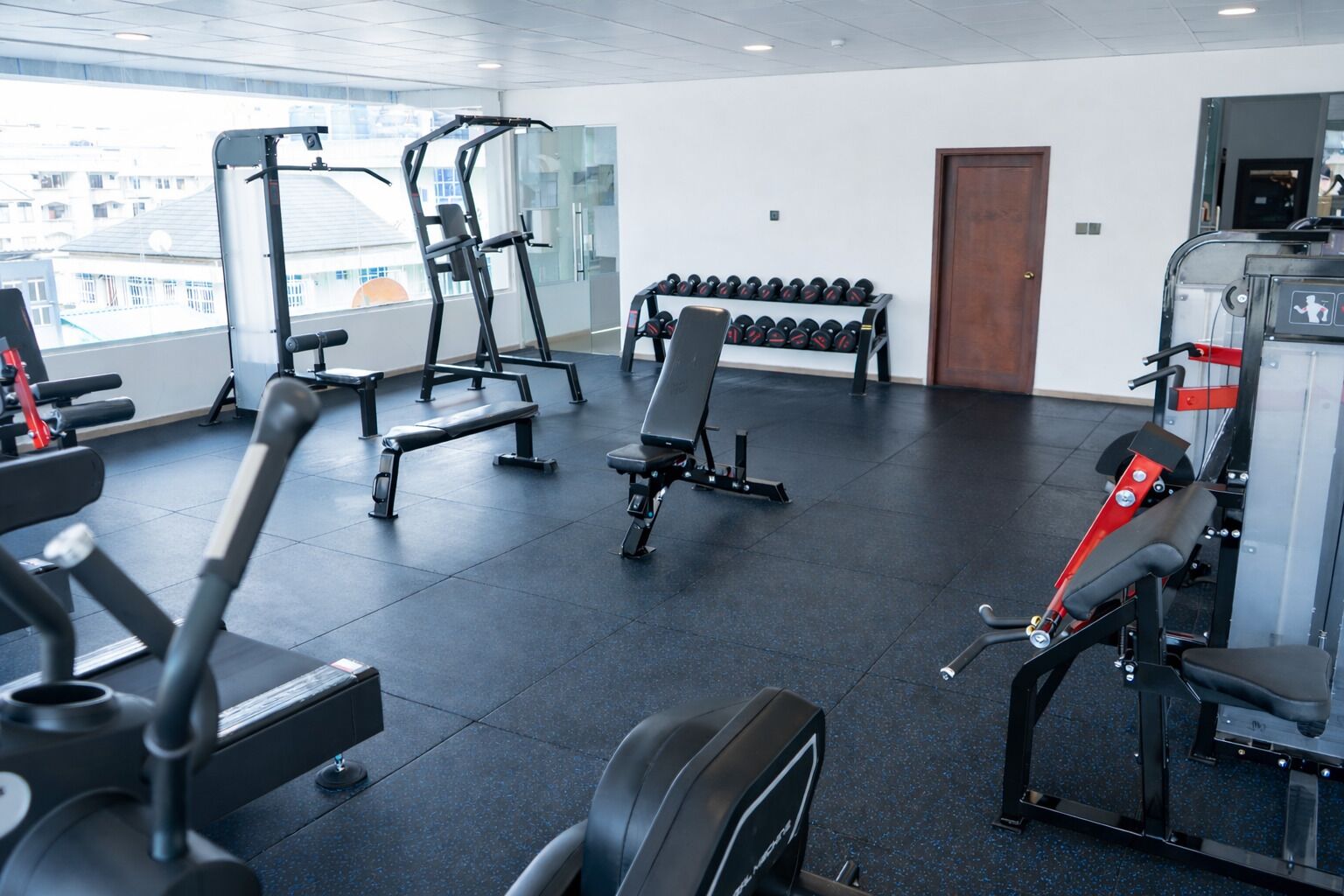 A gym with various exercise equipment, including treadmills, weight machines, and dumbbells.