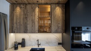A modern kitchen with a marble countertop, a sink, and wooden cabinetry. - 121A - Dosplain Panoramic Apartments | Odles (Santa Cristina Valgardena)