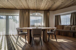 A dining area with a wooden table, four chairs, and a bench with cushions. - 121A - Dosplain Panoramic Apartments | Odles (Santa Cristina Valgardena)