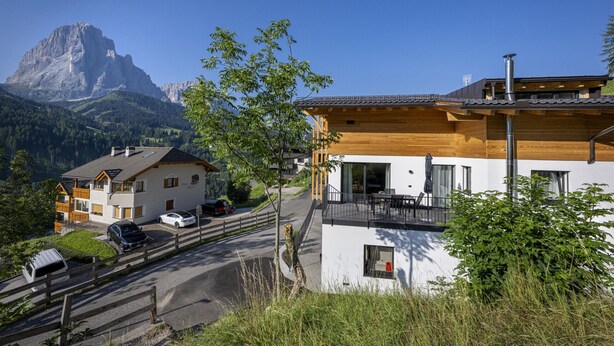 Eine Berglodge mit Holzfassade, einem Balkon und Blick auf einen Berggipfel.