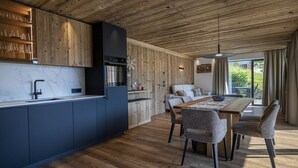 Eine moderne Küche mit Holzbalkendecke, Marmorarbeitsplatte und einem Essbereich mit Holztisch und -stühlen.