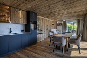 A modern kitchen with a wooden ceiling, a marble countertop, and a dining area with a wooden table and chairs. - 121B - Dosplain Panoramic Apartments | Meisules (Santa Cristina Valgardena)