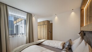Ein modernes Hotelzimmer mit einem großen Bett, einem Holzschrank und einem großen Fenster mit Vorhängen.