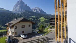 Ein Berggasthaus mit geparktem Auto davor, umgeben von üppigem Grün und einem markanten Berg im Hintergrund.