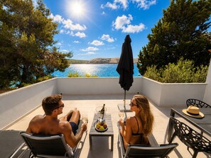 Una terraza con mesa, sillas y vista al mar.