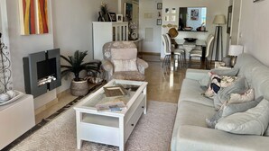 Un salon moderne comprenant un canapé, un fauteuil, une table basse et un téléviseur.