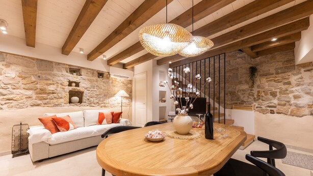 A dining area with a wooden table, black chairs, and a stone wall backdrop. - Casa di Pietra Stone House (Kaštel Lukšić)
