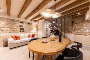 A dining area with a wooden table, black chairs, and a stone wall backdrop. - Casa di Pietra Stone House (Kaštel Lukšić)