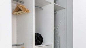 Valkoinen vaatekaappi, jossa on useita hyllyjä ja laatikoita, henkaritanko ja alaosassa taitettu vaatekappale.