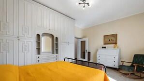 Un dormitori amb llit, armari, tauleta de nit i un quadre a la paret.