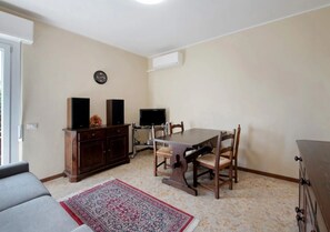 A dining area with a table, chairs, a TV, speakers, and a clock on the wall. - Apartment 'Solarolo Eleonora' with Balcony and Wi-Fi (Solarolo)