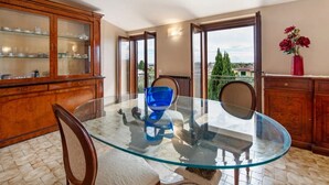 A dining area with a glass table, chairs, a wooden cabinet with glass doors, and a view through a glass door. - Apartment 'Solarolo Cristina' with Lake View, Wi-Fi and Air Conditioning (Solarolo)