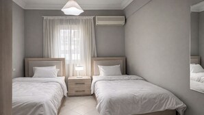 Un dormitorio con dos camas, una mesita de noche con lámpara, un equipo de aire acondicionado y un espejo grande.
