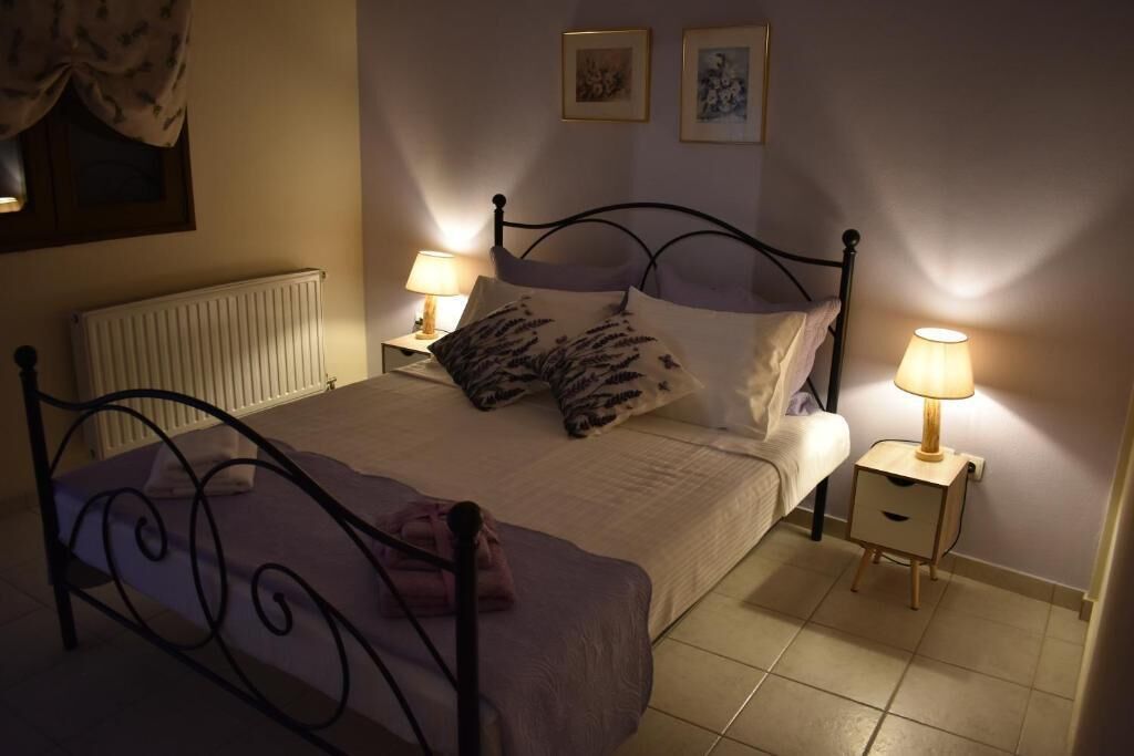 Cama bem arrumada com cabeceira, duas luminárias de cabeceira e uma pequena mesa de cabeceira com abajur.