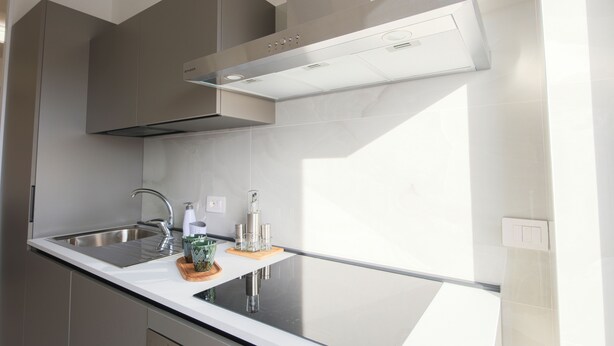 Una cocina moderna con un lavamanos de acero inoxidable, una campana extractora empotrada y un ventanal que proporciona luz natural.