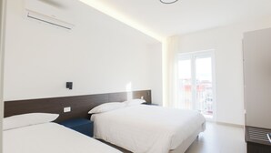 Habitación de hotel con dos camas, una ventana con vistas, una lámpara en el techo y un equipo de aire acondicionado.