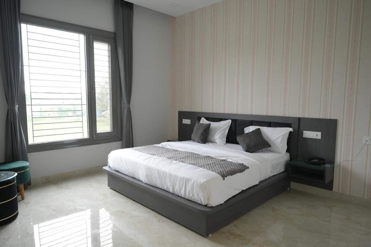 Quarto moderno com uma cama grande, mesa de cabeceira, janela com cortinas e papel de parede listrado.