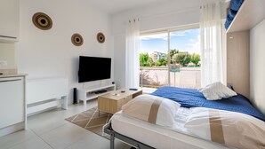 Una habitación de hotel moderna con una cama, televisión y un balcón con vistas a la ciudad.