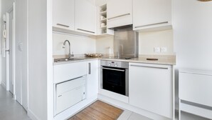 Una cocina moderna con armarios blancos, un horno Bosch, una campana de acero inoxidable y un tapete de madera.
