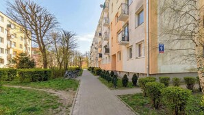 En bostadsbyggnad med balkonger, en asfalterad gångväg och en liten trädgårdsyta.