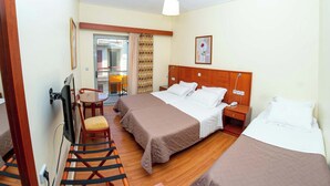 Ein Hotelzimmer mit zwei Betten, einem Schreibtisch, einem Stuhl, einem Fernseher und einem Balkon.