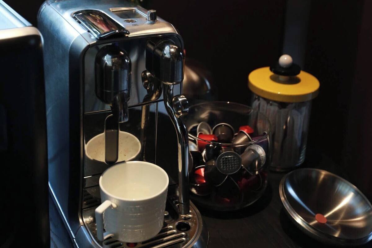 A coffee machine with a cup and a container of coffee pods.