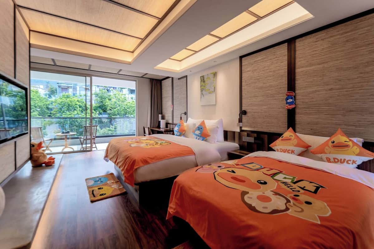 Een hotelkamer met twee bedden, een groot raam en een balkon.