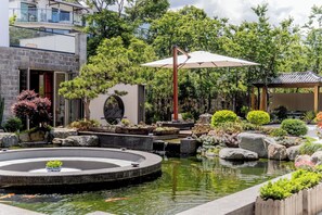 Un jardín sereno con un estanque de carpas, un sendero de piedra y un pabellón de estilo japonés tradicional.