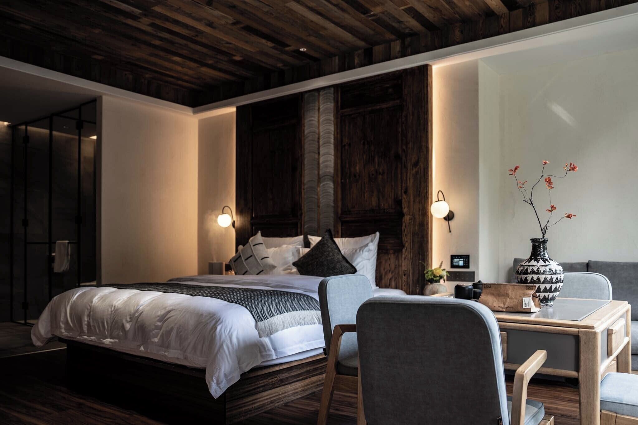 Ein modernes Schlafzimmer mit einem großen Bett, Nachttischen, einem Schreibtisch und einem Sessel.