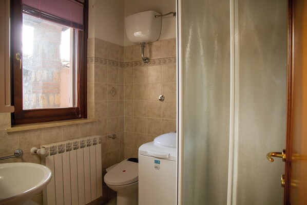 A bathroom with a toilet, a sink, and a window. - Casa Lino Saturnia (Manciano)