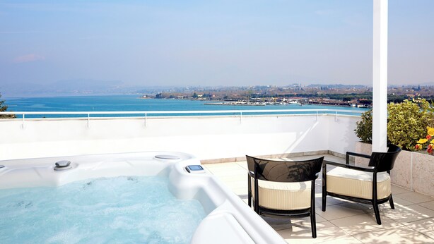 Terraço no telhado com hidromassagem, duas cadeiras e vista para o mar e a paisagem urbana.