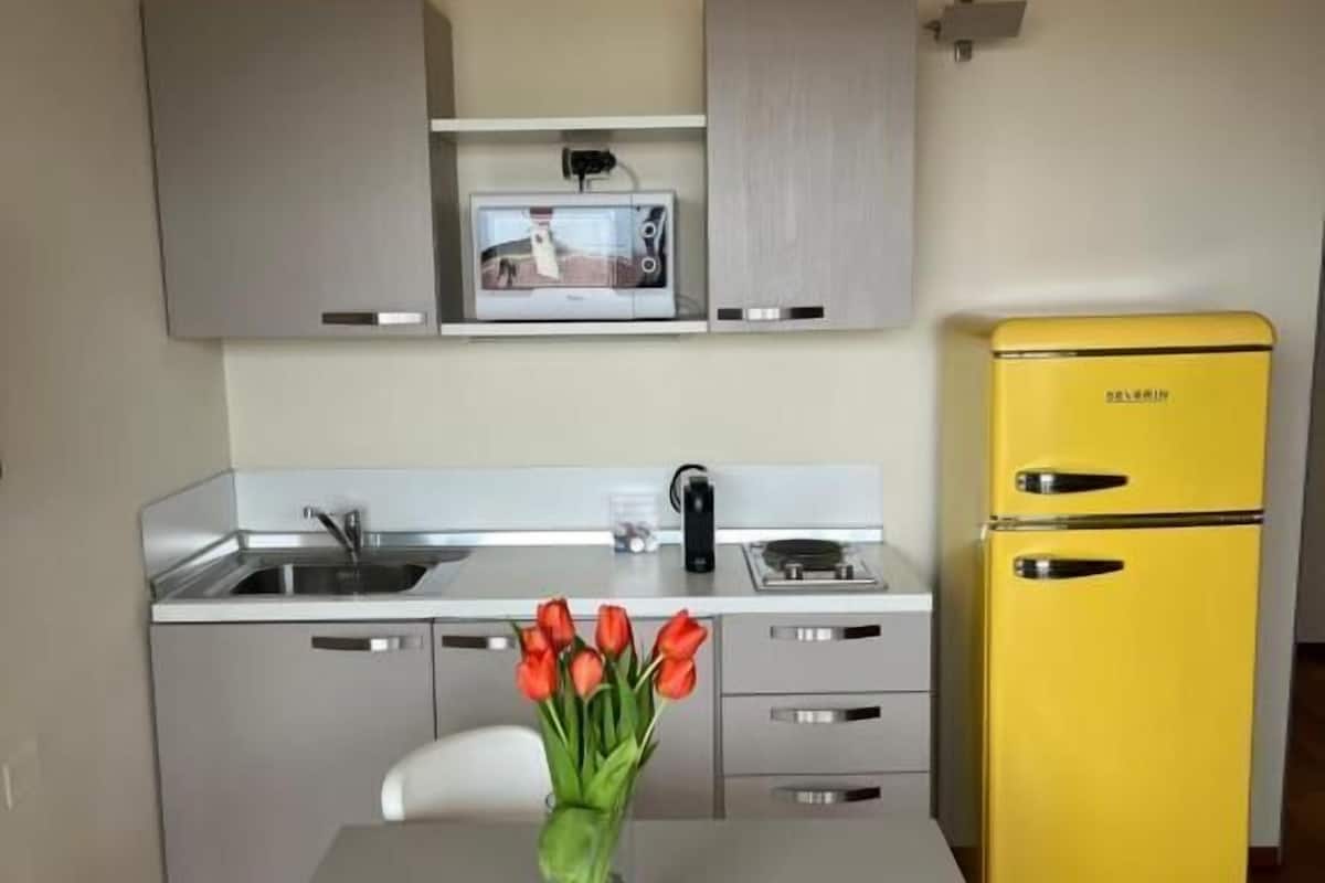 Eine kleine Küche mit einer Mikrowelle, einem Spülbecken und einem gelben Kühlschrank.