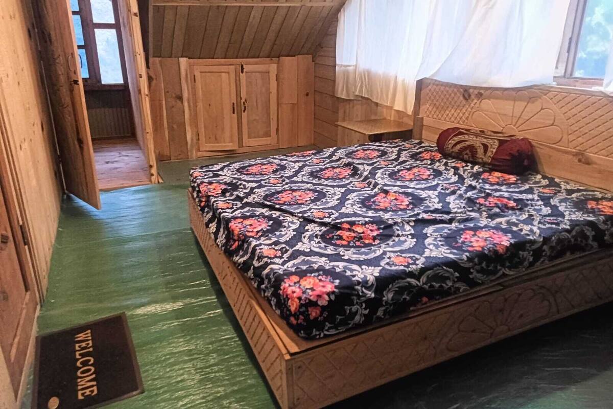Una stanza in legno con un letto, una porta e un tappetino di benvenuto.