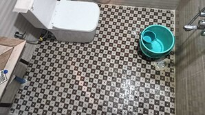 Kylpyhuone, jossa on wc, suihku ja ruutukuviollinen lattia.