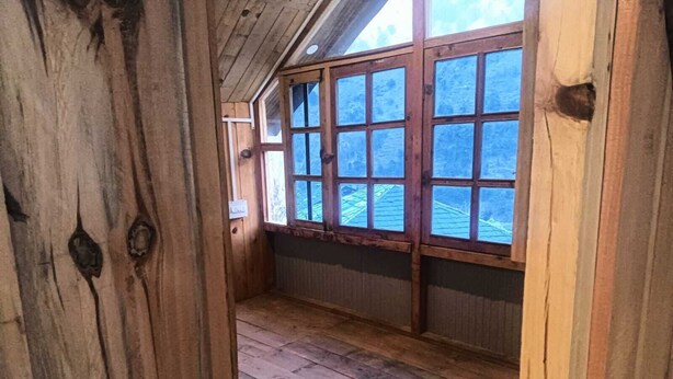Puinen sisustus, jossa on kalteva katto ja suuret ikkunat.