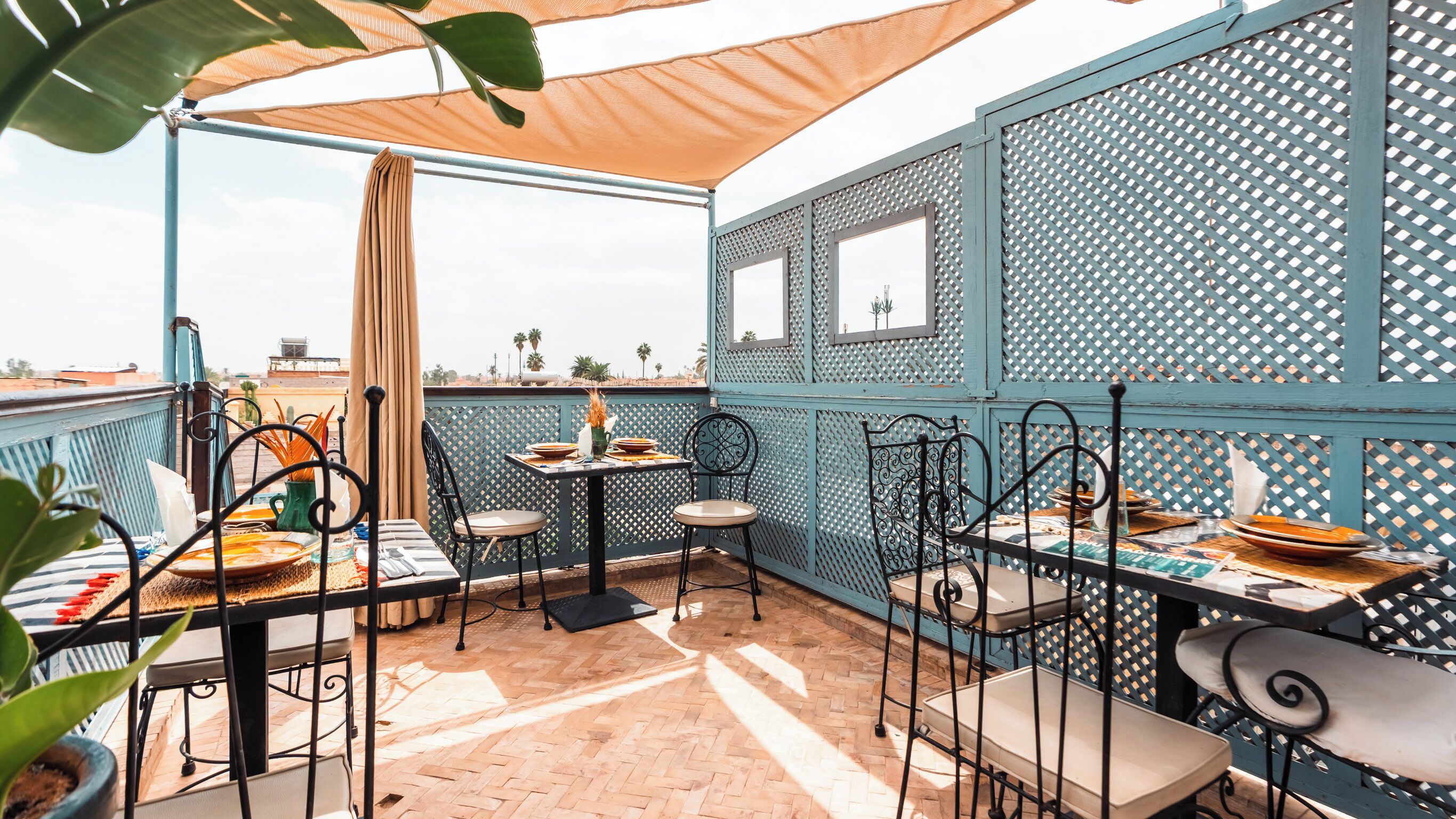 Un patio con mobiliario exterior, una mesa con platos y vistas a la ciudad.