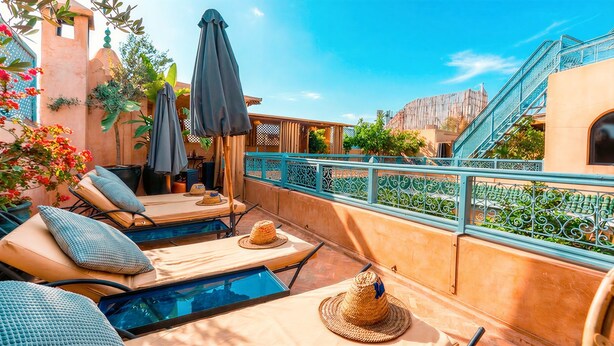 Eine Dachterrasse mit Liegestühlen, einem Pool und Blick auf ein Gebäude mit einer Treppe.