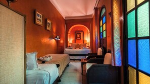 A hotel room with a bed, a chair, a desk, a lamp, and a view through a window with patterned glass. - Riad Dama & SPA (Marrakech)