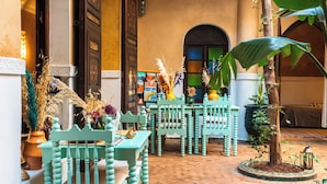 Ein Innenhof mit türkisfarbenen Stühlen, einem kleinen Tisch und einem Blumentopf.