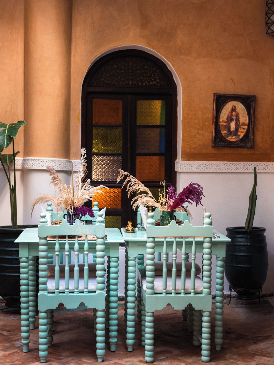 A dining area with a table and chairs, a decorative door, and a framed picture on the wall.