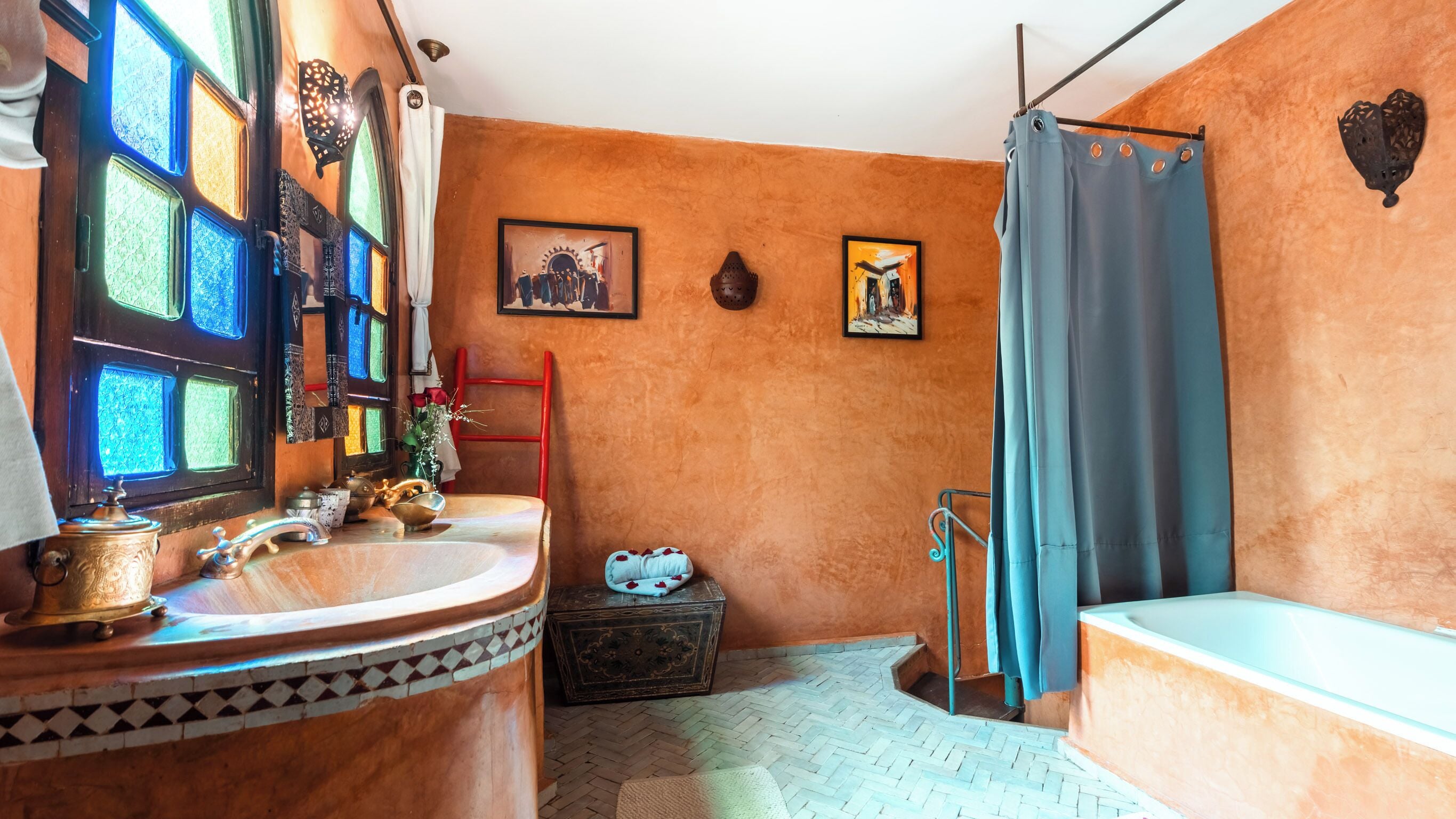 Une salle de bain avec un meuble-lavabo en bois, une baignoire, un rideau de douche et deux tableaux encadrés au mur.