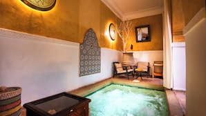 Ein Wellnessbereich mit Whirlpool, Sitzgelegenheiten, Wanddekoration und einem Spiegel.