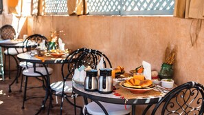 A dining table with a basket, two coffee pots, a plate of food, and a glass of juice. - Riad Dama & SPA (Marrakech)