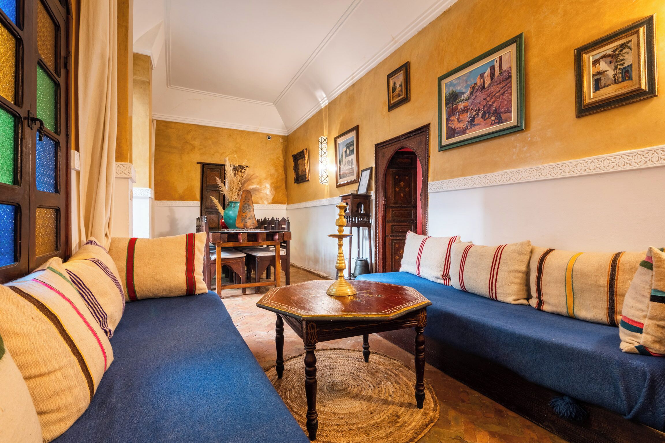 Une pièce avec un canapé bleu, une table en bois et un tapis à motifs.
