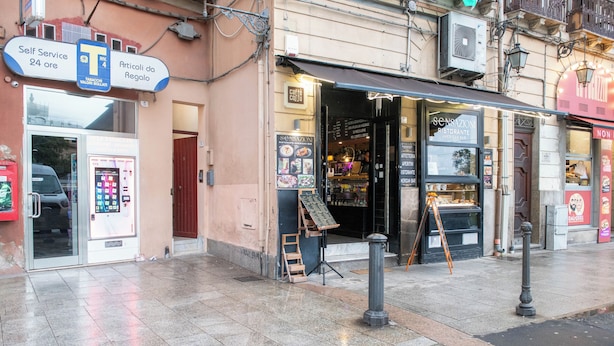 A storefront with a self-service kiosk, a sign for 'Articoli da Regalo', and a 'Caffè Coniglio' sign. - Yenne Home (Cagliari)