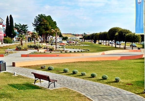 Ein Park mit einem gepflasterten Weg, Bänken und geschnittenen Hecken.