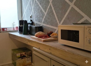 Eine Küche mit Mikrowelle, Toaster und Schneidebrett mit Lebensmitteln.