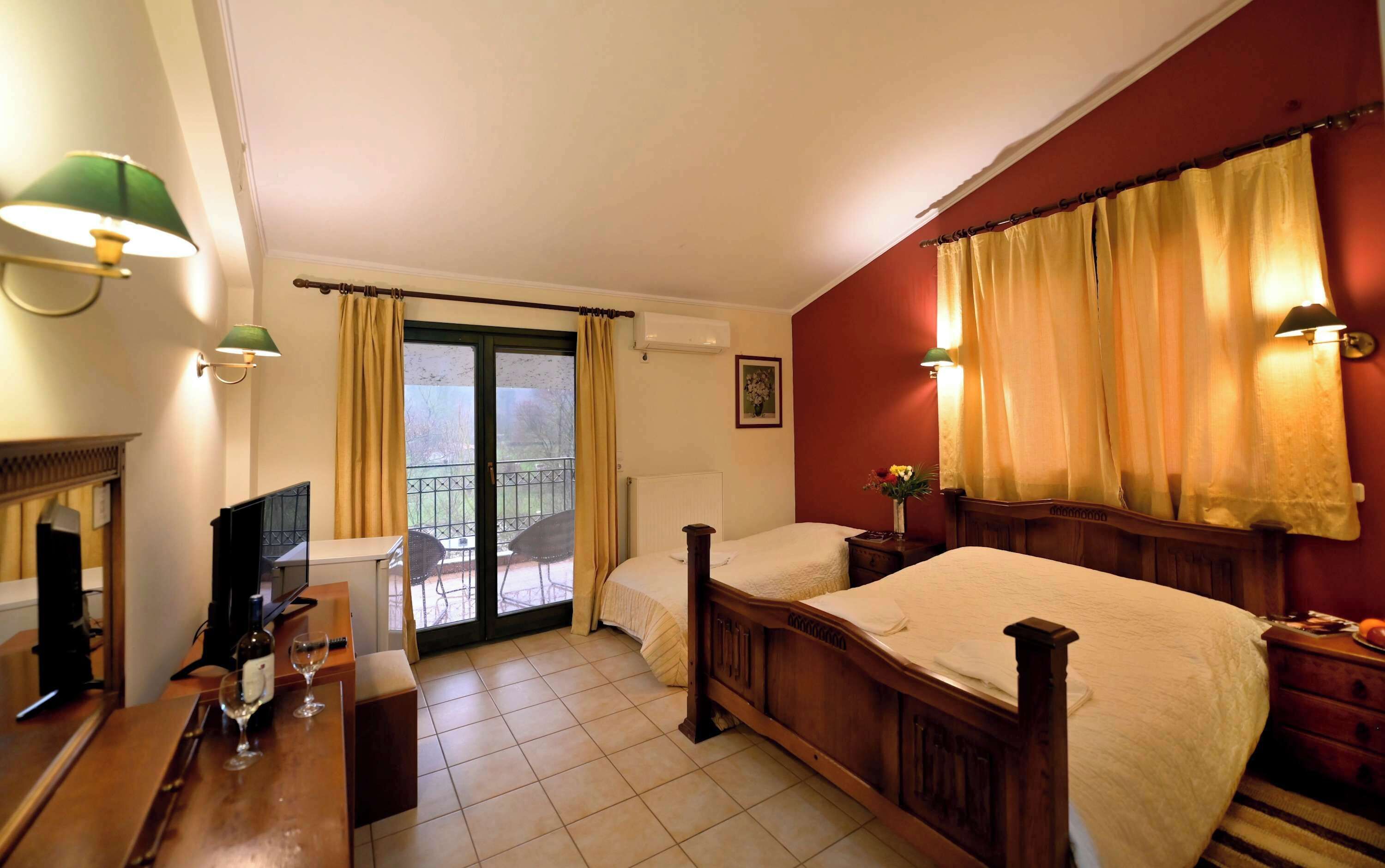 A hotel room with two beds, a desk with a chair, a TV, and a balcony with a view.