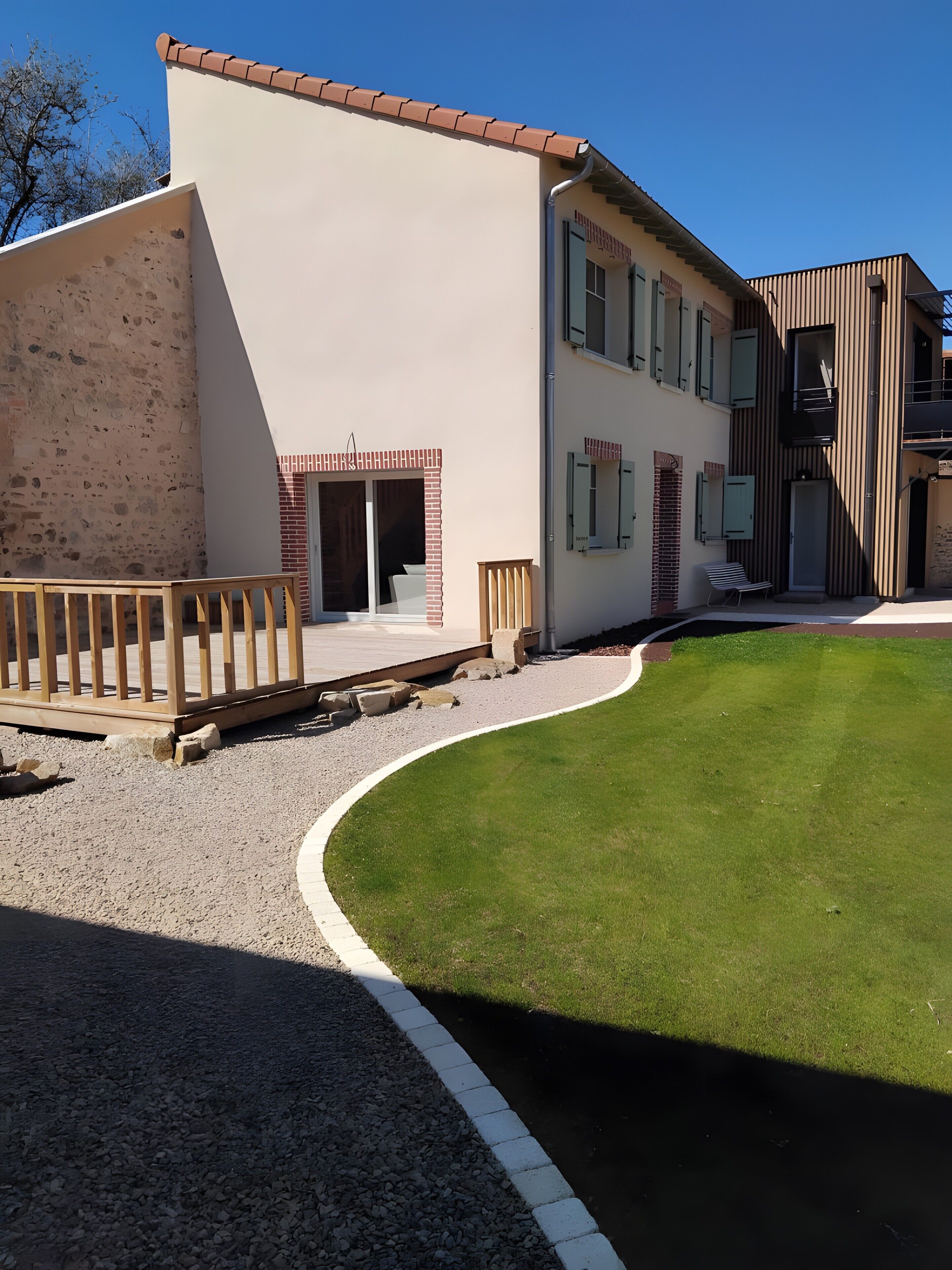 En moderne bygning med fladt tag, overdækket terrasse og velplejet græsplæne.