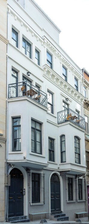 A multi-story building with a white facade, black-framed windows, and a balcony with ornate iron railings. - Nm Suites Beyoglu (Istanbul)
